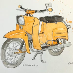 Op de afbeelding: Een aquarelillustratie van een gele Simson KR51 bromfiets met een zwart zadel, zilverkleurig stuur en spaakwielen. Het kunstwerk bevat oranje en zwarte verfspatten, met de tekst Simson KR51 en de handtekening Chris 26.