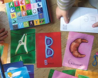 Könnte beinhalten: Ein Satz bunter Alphabet-Karteikarten mit Illustrationen verschiedener Gegenstände. Die Karten zeigen die Buchstaben A, B und C mit entsprechenden Bildern eines Affen, einer Brille und eines Croissants. Die Karten sind Teil eines größeren Satzes von Alphabet-Karteikarten.