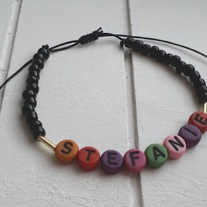 Könnte beinhalten: Ein schwarzes Armband mit bunten Perlen, die den Namen "Stefanie" buchstabieren.