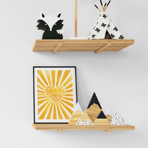 May include: A wooden shelf with a black and white fox figurine, a white teepee with black crosses, and a framed print with a yellow sunburst design and the text "You are my sunshine" in a white heart shape.
