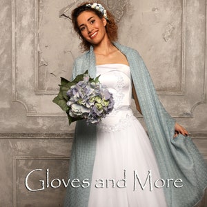 May include: A bride wearing a white strapless wedding dress with a light blue shawl and a flower crown. She is holding a bouquet of blue hydrangeas. The text "Gloves and More" is written in the bottom center of the image.