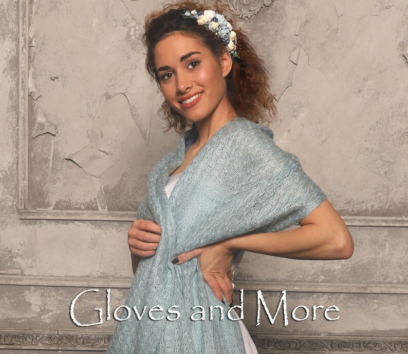 May include: A woman wearing a light blue knitted shawl with a floral headband. The text "Gloves and More" is visible at the bottom of the image.