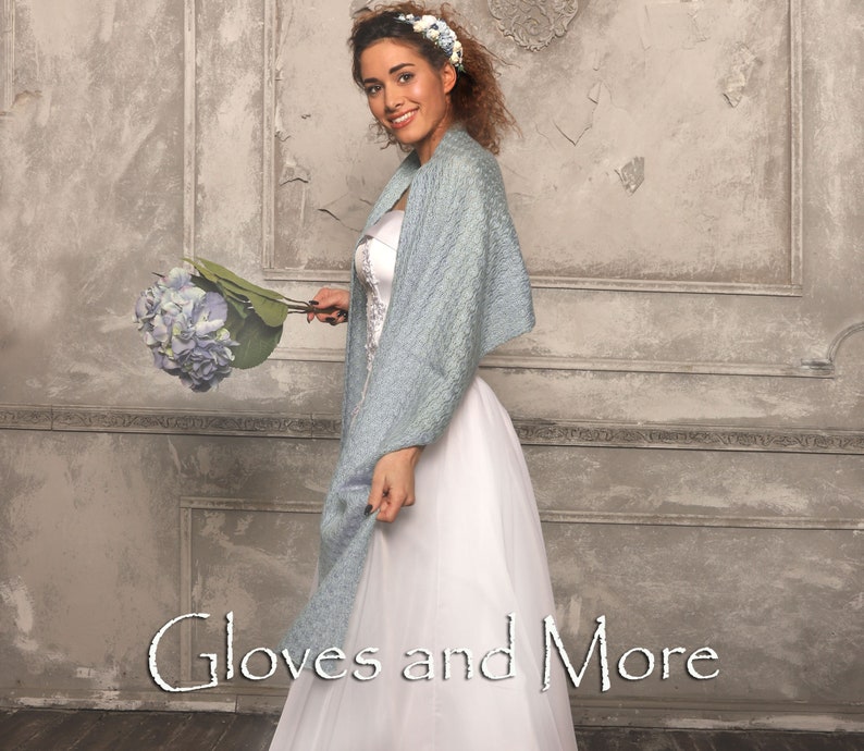 May include: A woman wearing a white dress and a light blue shawl holds a bouquet of blue flowers. The text "Gloves and More" is visible at the bottom of the image.