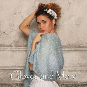 May include: A woman wearing a light blue knitted shawl with a floral headband. The text "Gloves and More" is visible at the bottom of the image.