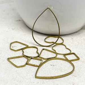 May include: A set of 10 gold metal jewelry making shapes, including a teardrop, heart, square, and other geometric shapes.