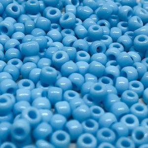 Könnte beinhalten: Ein großer Haufen hellblauer Perlen. Die Perlen sind klein und rund und perfekt zum Basteln.