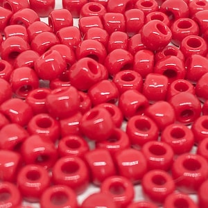 Könnte beinhalten: Ein großer Haufen roter Plastikperlen. Die Perlen sind rund und haben ein Loch in der Mitte. Sie sind perfekt zum Basteln und für die Schmuckherstellung.