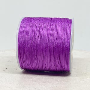 Op de afbeelding: Een spoel met paarse gewaxt koord, perfect voor het maken van sieraden, macramé of knutselen.