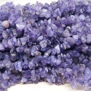 Könnte beinhalten: Nahaufnahme einer Schnur aus hellvioletten Amethyst-Chips. Die Perlen sind unregelmäßig geformt und haben eine leicht durchscheinende Optik.