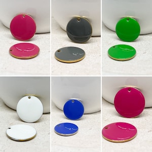 Op de afbeelding: Assortiment van 10 ronde, platte, geëmailleerde metalen bedels met een gouden rand. De bedels zijn in verschillende kleuren, waaronder roze, groen, blauw, grijs en wit.