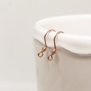 May include: Two rose gold earring hooks with a twisted wire design.