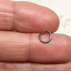 May include: A silver jump ring, a small metal ring used for connecting jewelry components.