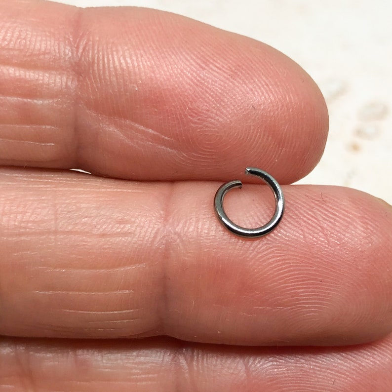 May include: A silver jump ring, a small metal ring used for connecting jewelry components.