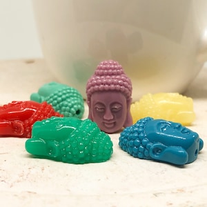 Könnte beinhalten: Sortiment an bunten Buddha-Kopfperlen, jede mit einer einzigartigen, strukturierten Oberfläche. Die Perlen sind in den Farben Rot, Grün, Blau, Gelb und Lila.