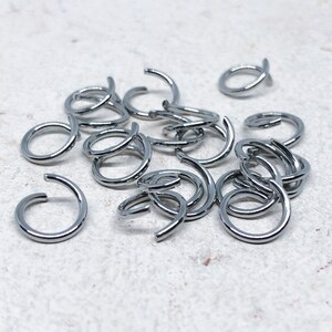 May include: A pile of silver jump rings, a type of jewelry finding used for connecting jewelry components.