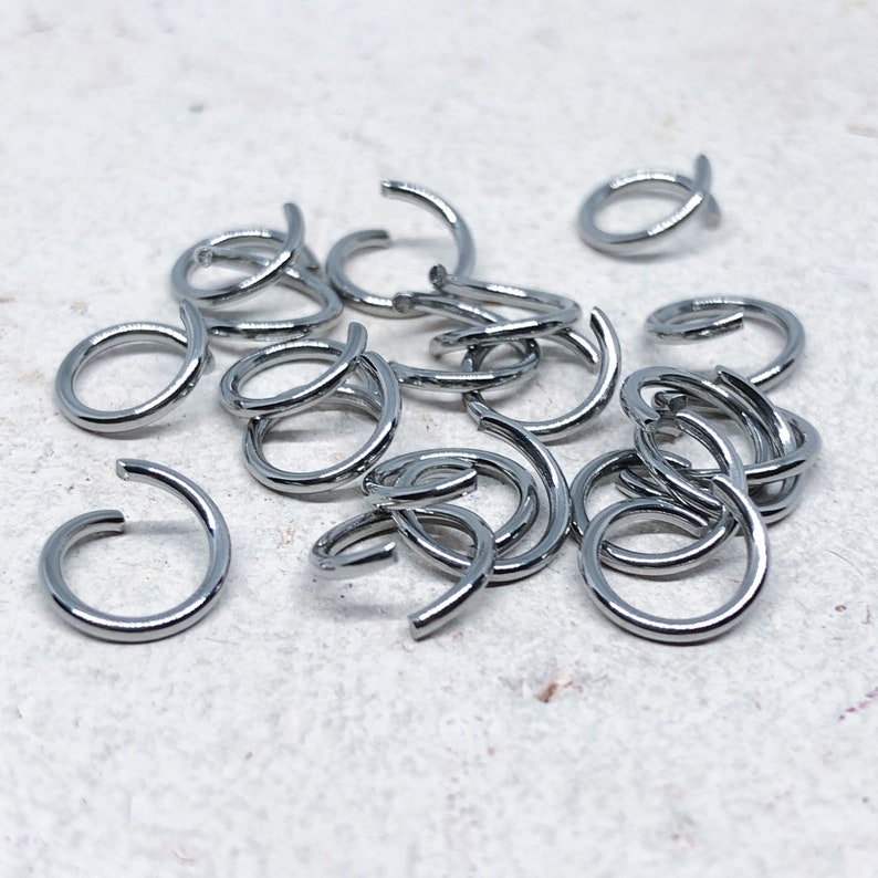 May include: A pile of silver jump rings, a type of jewelry finding used for connecting jewelry components.