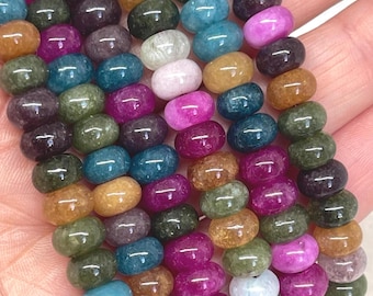 May include: A collection of smooth, round, donut-shaped beads in a variety of colors including deep pink, teal, olive green, amber, and white. These polished gemstone beads are arranged in multiple vertical strands, showcasing a glossy finish.