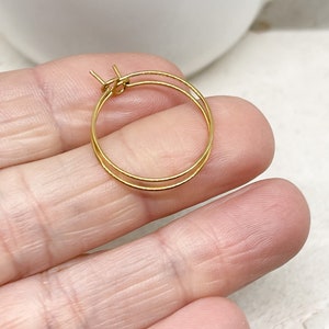 May include: A pair of gold hoop earrings. The earrings are small and delicate, and they are perfect for everyday wear.