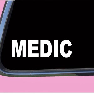 May include: White vinyl decal with the word "MEDIC" in bold, white letters on a black background.