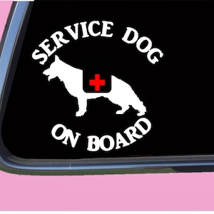 May include: White vinyl sticker featuring a silhouette of a German Shepherd service dog wearing a red medical cross vest. The text "SERVICE DOG ON BOARD" is in a white circle around the dog.