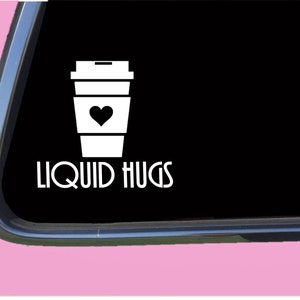 May include: White vinyl sticker with a coffee cup and the text "LIQUID HUGS". The coffee cup has a heart in the center.
