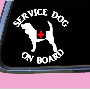 May include: White vinyl decal with a black background. The decal features a silhouette of a dog with a red cross on its back. The text "SERVICE DOG ON BOARD" is written in a circle around the dog.