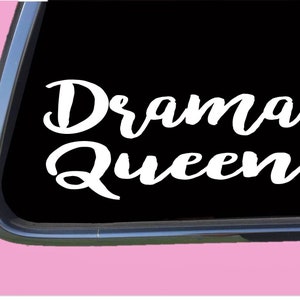 May include: White vinyl decal with the text "Drama Queen" on a black background. The decal is designed to be placed on a car window.