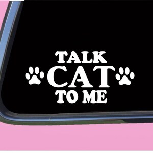 May include: White vinyl decal with the text "Talk Cat To Me" and two paw prints on a black background.