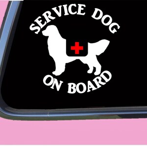 May include: White vinyl sticker with a black background. The sticker features a white silhouette of a dog with a red cross on its back. The text "SERVICE DOG ON BOARD" is written in a circle around the dog.