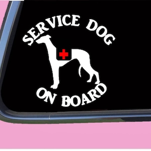 May include: White vinyl sticker with a black background. The sticker says "SERVICE DOG ON BOARD" in a white arc with a white silhouette of a dog with a red cross on its back.