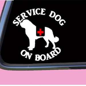 May include: White vinyl sticker with a silhouette of a dog and the text "SERVICE DOG ON BOARD". The dog is wearing a red cross on its back.