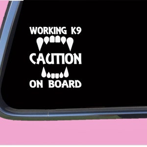 May include: White vinyl sticker with the text "WORKING K9 CAUTION ON BOARD" and a graphic of a dog's teeth.