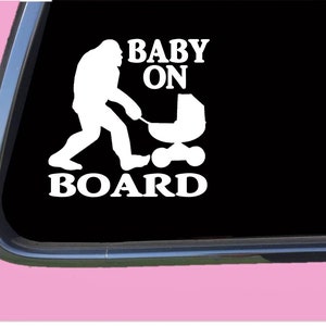 May include: White vinyl sticker with a silhouette of a Bigfoot pushing a baby stroller. The text reads "Baby On Board".