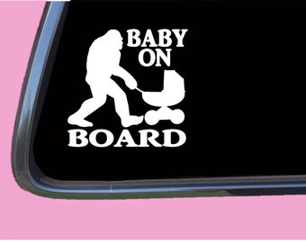 May include: White vinyl sticker with a silhouette of a Bigfoot pushing a baby stroller. The text reads "Baby On Board".
