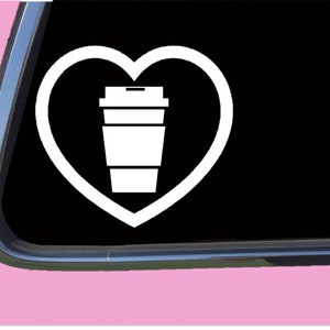 May include: White vinyl decal of a coffee cup inside a heart. The decal is ideal for a car window or laptop.