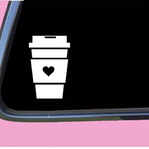 May include: White silhouette of a coffee cup with a heart on the side. The cup is a takeaway cup with a lid.
