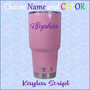May include: A pink Yeti tumbler with the name "Sophia" in purple script on the side. The tumbler has a stainless steel lid and base. The text "YETI" is printed in silver on the side of the tumbler. The text "Kaylar Script" is printed in purple at the bottom of the image.