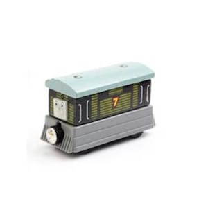 Op de afbeelding: Een houten speelgoedtreinwagon met een lichtblauw dak en een grijze basis. De zwarte zijkanten hebben verticale lijnen en het nummer 7 in geel. De voorkant van de trein heeft een gezicht en een zilveren koplamp.