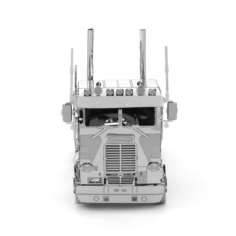 Op de afbeelding: Een zilverkleurig metalen model van een vrachtwagen, van voren gezien. De vrachtwagen heeft gedetailleerde kenmerken zoals een grille, koplampen, uitlaatpijpen en zijspiegels. Het model staat tegen een witte achtergrond.