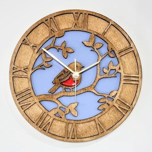 May include: A wooden clock with a blue background and a cut-out design of a bird on a branch. The clock face has Roman numerals.