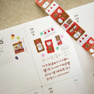 Könnte beinhalten: Ein Planer mit Wochenansicht, verziert mit bunten Aufklebern und einem gemusterten Washi-Tape. Die Aufkleber zeigen Desserts und Getränke. Das Washi-Tape zeigt sich wiederholende Bilder von Kuchen, Erdbeeren und Kaffeetassen. Handschriftlicher Text ist sichtbar.