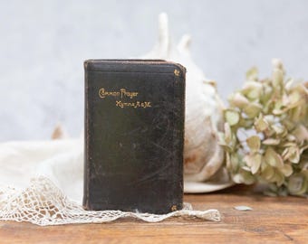 May include: A small, black leather-bound book with gold lettering that reads "Common Prayer Hymns A. & M."