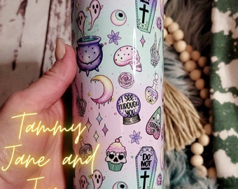 May include: A pastel-colored tumbler featuring a whimsical design with ghosts, skulls, cauldrons, and a crystal ball. The tumbler has the text "I see through you" and "Do Not". The tumbler is cylindrical and appears to be made of stainless steel.