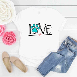 May include: White t-shirt with a black and white graphic of the word "LOVE" with a blue paw print in the "O".
