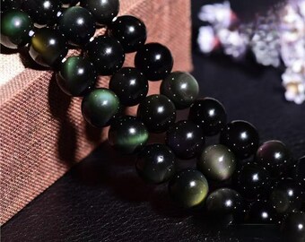 May include: A strand of black and green gemstone beads. The beads have a shimmering, iridescent effect.