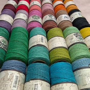 May include: A collection of colorful hemp cord spools in various shades, including green, blue, pink, and orange. Each spool is labeled with "Hemp Cord" and a map design. Some spools have numbers printed on them. The cord appears to be 1.0mm thick.