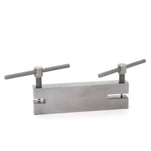 May include: A metal punch tool with two adjustable handles. The tool has a rectangular base with a cut-out in the centre.