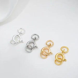 May include: Three silver and gold lobster clasps for jewelry making. The clasps are made of metal and have a polished finish.