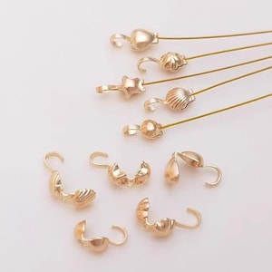 Puede incluir: Surtido de cierres y tapas de extremo de metal dorado para la elaboración de joyas. Los cierres son de varias formas, incluyendo corazón, estrella, concha y redondos.