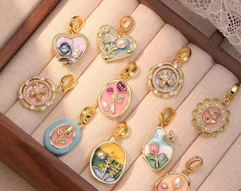 May include: A collection of gold-toned pendants with floral and pearl designs. The pendants feature various shapes, including hearts, ovals, and circles, with colorful enamel and intricate detailing. Each pendant has a loop for attaching to a chain.